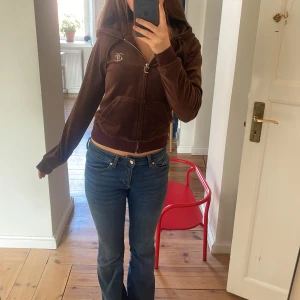Brun Juicy Couture tröja - Säljer en brun hoodie från Juicy Couture med dragkedja och huva. Den har ett glittrigt Juicy-tryck på ryggen och en liten logga på bröstet. 