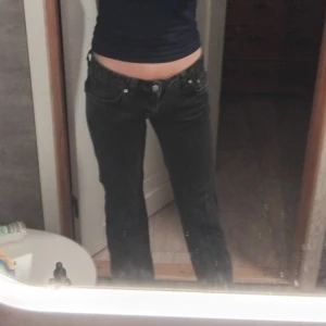 Svarta jeans med låg midja - Snygga svarta jeans med låg midja och klassisk femficksdesign. Perfekta för en avslappnad stil. De har en rak passform och är tillverkade i ett slitstarkt material.