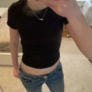 Svart croppad t-shirt - Säljer en svart croppad t-shirt med korta ärmar. Perfekt för en avslappnad stil och kan enkelt matchas med jeans eller kjol. Passar även bra som xs!
