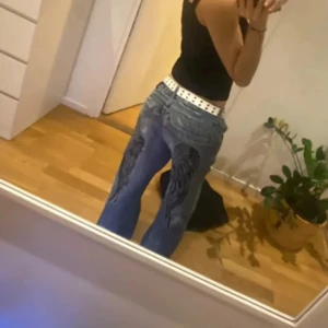Baggy jeans - Med slitna detaljer. Från kosmo lupo. Klippta o sydda längst ner skriv för bilder och har broderi på baksidan som är väldigt coolt. Baggy och passar någon runt längden 160. Står ingen storlek men skulle uppskatta S i och med att längden är runt för någon 160 och midjan är väldigt stor och det är därför jag sytt där, men kan sprätta bort om man vill. Ena fickan är lite trasig men ser coolt ut. Innerbenslängd: ca 70cm