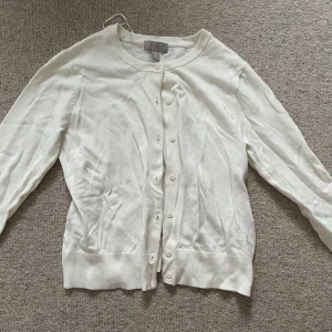 Vit kofta från H&M - Säljer en klassisk vit kofta från H&M med knappar framtill. Den har långa ärmar och en rund halsringning, perfekt för lager-på-lager-stil. Passar till många olika outfits och tillfällen💞säljer pga att jag inte använder den.