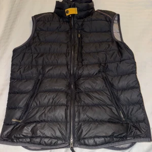 Parajumper lightweight dunväst  - Säljer en svart dunväst från Parajumpers med dragkedja och hög krage. Västen har en quiltad design och praktiska fickor med dragkedjor. Perfekt för kyliga dagar. Litet hål i ryggen 