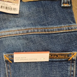 Blåjeans från Nudie - nya - Snygga blå jeans från Nudie Jeans i ekologisk bomull av modell Thin Finn. De har en klassisk femficksdesign med dragkedja och knapp. Perfekta för en stilren look med en bekväm passform. Helt nya! 
