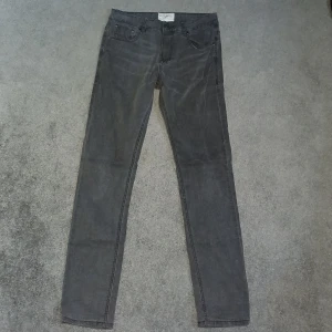 Grå jeans från Bruun & Stengade - Snygga grå jeans från Bruun & Stengade i en klassisk straight fit. Perfekta för en stilren look med fem fickor och knappgylf. Tillverkade i ett slitstarkt material som ger en bekväm passform.