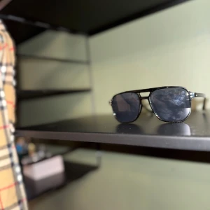 Svarta solglasögon med dubbel brygga - Snygga svarta solglasögon med en modern dubbel brygga och rektangulära linser. Perfekta för en stilren look. De har en klassisk design som passar de flesta ansikten och ger ett coolt intryck.