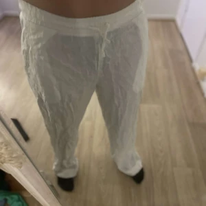 Vita linnebyxor med snörning - Snygga vita linnebyxor med avslappnad passform och snörning i midjan. Perfekta för varma sommardagar med sitt lätta och luftiga material. Byxorna har en loose stil som ger en bekväm känsla. 