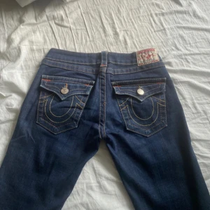 Mörkblå jeans True Religion - Säljer ett par snygga mörkblå jeans från True Religion i storlek 28. De har en klassisk femficksdesign med coola sömmar och knappar. Perfekta för både vardag och fest! 🕺