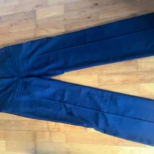 Blå höga kostymbyxor  - Säljer nu ett par högmidjade mörkblå kostymbyxor från madlady. Bra skick men använda en del. Säljer endast för de är för små