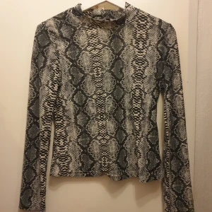 Ormmönstrad långärmad topp från Shein - Säljer en supercool ormmönstrad topp från Shein. Den är långärmad och har en tight passform, perfekt för en utekväll eller när du vill sticka ut lite extra. Materialet är mjukt och stretchigt, vilket gör den bekväm att bära. Passar perfekt till både jeans och kjol! Märkt L men passar s/m bättre 