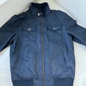 Helt Ny elegans jacka, Endast 79 Kr. - Denna fantastiska skinnjacka från C@A. perfekt för skolans dagar  eller speciella tillfällen.  Denna jacka är helt ny och utan prislapp.Den är i storlek 152 . Ordinarie priset är 599 kr men du kan nu äga denna vackra skinnjacka för endast 79 kr. 