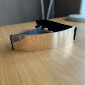 Midjebälte med guldspänne - Helt ny midjebälte från H&M med en bred guldfärgad metallplatta framtill och elastiskt svart band. Perfekt för att ge en stilren touch till din outfit. Etiketterna och skyddsplast är fortfarande på. 