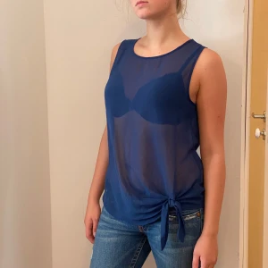 Blå ärmlös topp från Esmara - Säljer en snygg blå ärmlös topp från Esmara i storlek S/M.Toppen är i ett lätt och luftigt material, perfekt för sommardagar. Den har en knytning i sidan och knappar i ryggen för en extra touch. Passar både till vardags och fest!