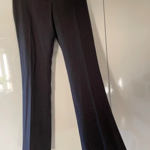 Kostymbyxor - Lätt utsvängda kostymbyxor med tunna blå ränder i storlek xs/s. Köpta vintage