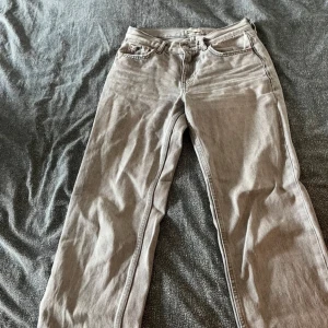 Grå jeansbyxor - Säljer ett par grå jeansbyxor i bra skick. De har en klassisk design med fem fickor och en knappgylf. Perfekta för vardagsbruk och kan matchas med nästan vad som helst. Passformen är normal och de är riktigt bekväma att ha på sig.