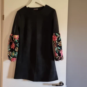 Kort klänning - Kort klänning med lite puffiga o blommiga ärmar. Sparsamt använd