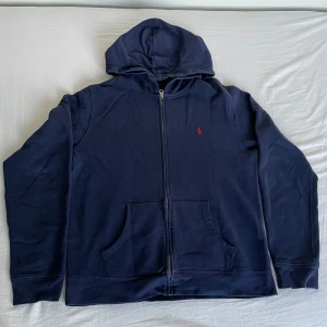 Ralph lauren hoodie - Skitsnygg blå ralph lauren zip-up hoodie med röd logga🔥 Originalpris runt 1600. Bra skick förutom små defekter (se bild 3,4) men inget som syns med hoodien på.