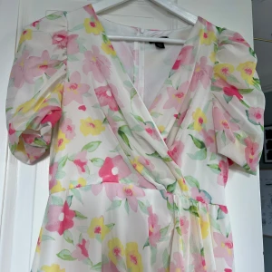 Blommig klänning  - Snygg blommig klänning med slits och vadderade axlar.  Använd 1 gång. 