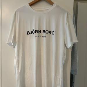 Säljer en stilren vit t-shirt från Björn Borg med texten 'BJÖRN BORG SINCE 1956' tryckt i svart på bröstet. Perfekt för en casual look, passar både till vardags och träning. T-shirten är i nyskick och har en normal passform.