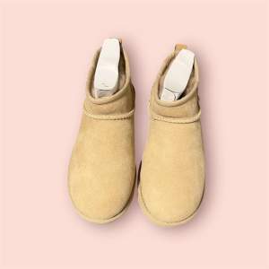 Säljer ett par snygga och bekväma beige boots från UGG i mocka. De har en klassisk design med rund tå och en mjuk insida som håller fötterna varma. Perfekta för höst och vinter! Sulan har ett bra grepp för hala underlag.