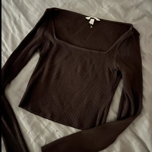 Tröja med fyrkantig halsringning - En mörkbrun fin tröja/topp med fyrkantig halsringning, inga defekter, typ aldrig använd, till och med plasten som lappen hänger i är kvar. Köptes för cirka 250kr