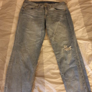 Ljusa jeans med slitningar - Säljer ett par ljusa boyfriend jeans med en cool slitning på ena benet. De har en klassisk femficksdesign och en bekväm passform. Perfekta för en avslappnad stil! Storlek 42. Men jag har m och använt dom som lite baggy jeans.  Jättesköna på!