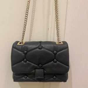 Svart väska - ZARA  - Jättefin svart väska från Zara med gulddetaljerat axelband. Har använts ett par gånger men är fortfarande i bra skick. Vid frågor är det bara att höra av sig🫶