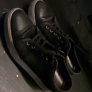 Svarta sneakers från Lanvin - Snygga svarta sneakers från Lanvin med klassisk design. Skorna har snörning och en vit sula som ger en stilren kontrast. Perfekta för en avslappnad men ändå elegant look. Lite slitna och så men ser fortfarande bra ut👍