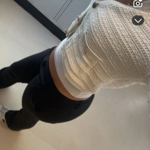 Vit stickad kofta från Bershka - Säljer en stilren vit stickad kofta från Bershka med knappar framtill och två fickor. Koftan är croppad och har långa ärmar, perfekt för en trendig look. Passar bra till både jeans och kjol. 🧶✨