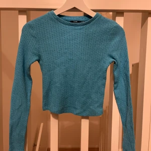 Blå ribbad tröja från Kiabi - Säljer en snygg blå ribbad tröja från Kiabi. Tröjan har en enkel design med långa ärmar och en rund halsringning. Perfekt för en avslappnad stil.