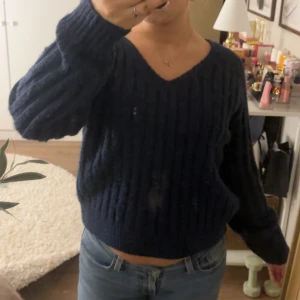 Mörkblå stickad tröja - Säljer en mysig mörkblå stickad tröja med v-ringning. Tröjan har långa ärmar och en ribbad design som ger en stilren look. Perfekt för kyligare dagar💗