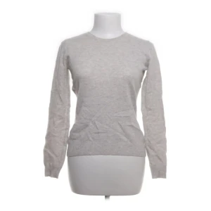 Grå kashmirtröja - Säljer en elegant grå tröja i 100% kashmir. Tröjan har en klassisk design med rund hals och långa ärmar. Perfekt för att hålla dig varm och stilren under kyligare dagar.