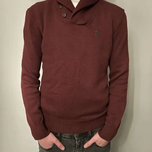 Vinröd tröja från Polo Ralph Lauren - Säljer en stilren vinröd tröja från Polo Ralph Lauren. Tröjan har en unik krage med knappar och det klassiska broderade logotypen på bröstet. Perfekt för en elegant och avslappnad look.