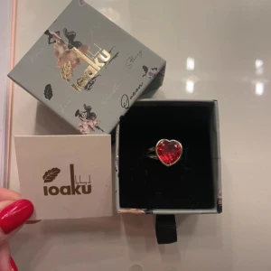 Ring med röd hjärtformad sten från Ioaku - Elegant ring från Ioaku med en stor röd hjärtformad sten. Perfekt för att ge en romantisk touch till din stil. Kommer i en fin presentask.