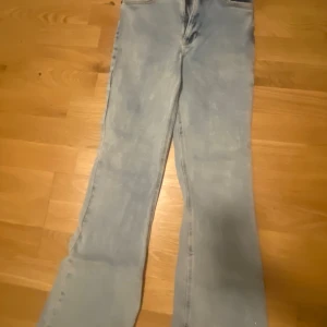 Ljusblå bootcut jeans - Säljer ett par ljusblå bootcut jeans med klassisk femficksdesign. De har en dragkedja och knapp framtill. Perfekta för en avslappnad stil.