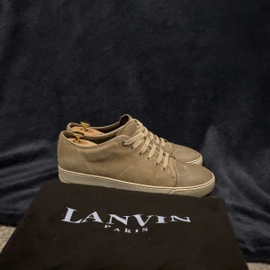 Bruna sneakers, Lanvin - Snygga bruna sneakers från Lanvin i mocka med klassisk snörning. Perfekta för en stilren look. Skorna har en diskret design med en ljus sula som ger en fin kontrast.