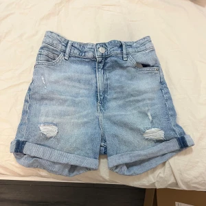 Blå jeansshorts med hög midja - Snygga blå jeansshorts från hm med hög midja och avslappnad passform. Shortsen har slitna detaljer och uppvikta ben för en trendig look. Perfekta för en avslappnad stil.