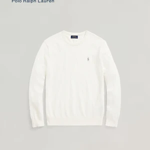 Vit/beige tröja från Polo Ralph Lauren - Säljer en stilren vit tröja från Polo Ralph Lauren med deras ikoniska logga broderad på bröstet. Tröjan har långa ärmar och en klassisk passform, perfekt för en elegant look. Tillverkad i ett mjukt material som ger en bekväm känsla. Autentiskt med qr kod 