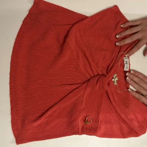 Röd omlottlinne från Zara - Säljer ett snyggt rött omlottlinne från Zara med tunna axelband och knytdetalj framtill. Perfekt för varma dagar eller sommarens fester. Materialet är lätt och luftigt.
