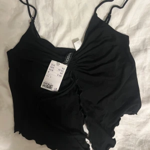 Svart sommartopp - Säljer en jättefin svart sommartopp som är öppen vid magen och lite croppad. Den har inte används då lappen även är kvar.