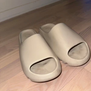 Yeezy slides  - Riktigt sköna Yeezy slides. Storlek 43-44 fast passar även mindre fötter. Bra skick lite smutsiga men det går lätt att göra rent. Säljs för att jag inte använder dem så mycket. 