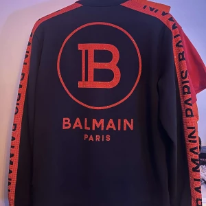 Svart zip från Balmain - Snygg svart zip från Balmain med röda detaljer och logotyp på ryggen. Nypris 9500 mitt pris 6500. Hör av dig om du har frågor.😁 Kvitto finns också.
