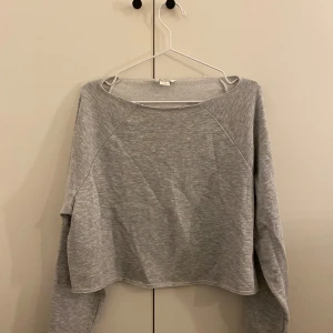 Grå croppad tröja - Säljer en stilren grå croppad tröja med långa ärmar. Perfekt för en avslappnad look. Passar bra till jeans eller kjol.