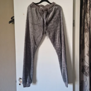 Grå mjukisbyxor från Isabella - Mysiga grå mjukisbyxor från Isabella i storlek S. Byxorna har ett diskret mönster och är tillverkade i ett mjukt material med resår och snörning i midjan för extra komfort.