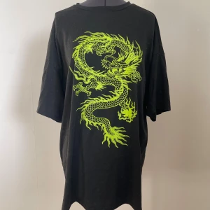 Svart t-shirt med draktryck - Svart t-shirt med ett stort neongrönt draktryck på framsidan.