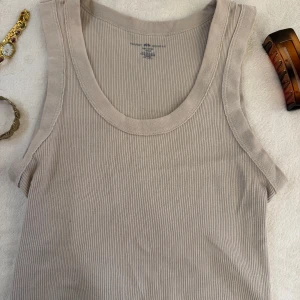 Beige topp från Brandy Melville - Säljer en stilren beige topp från Brandy Melville. Perfekt för varma dagar med sin ärmlösa design och mjuka material. Passar utmärkt till både jeans och kjol.