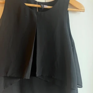 Svart ärmlös klänning från Divided - Snygg svart ärmlös klänning från Divided. Perfekt för en stilren look med sin enkla design och lätta material. Klänningen har en diskret dragkedja i ryggen för enkel påklädning.