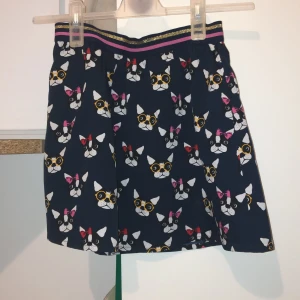 Mönstrad kjol från Holly & Whyte - Söt kjol från Holly & Whyte med ett lekfullt kattmönster i olika färger. Kjolen har en elastisk midja med glittriga detaljer i rosa och guld. Perfekt för den som gillar djurmotiv och vill ha något unikt i garderoben! Passar kanske mer åt mindre barn då jag säljer den för att den inte var min stil längre. Storlek 146-152, bra skick. Pris kan diskuteras