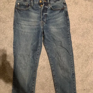 Blå jeansbyxor från märket Redefined Rebel  - Klassiska blå jeansbyxor med dragkedja och knapp. De är i modellen regular fit  och har fyra fickor. Perfekta för en avslappnad stil. Storlek: 29/32.