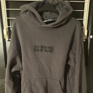 Grå hoodie från Palm Angels - Säljer en stilren grå hoodie från Palm Angels. Den har en klassisk design med en stor huva och en diskret logga på bröstet. Perfekt för en avslappnad look.