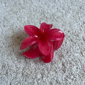 Rosa hårklämma i form av en blomma - Snygg rosa hårklämma formad som en blomma. Perfekt för att ge en färgglad touch till din frisyr. Klämman har en stark greppfunktion och är lätt att använda.